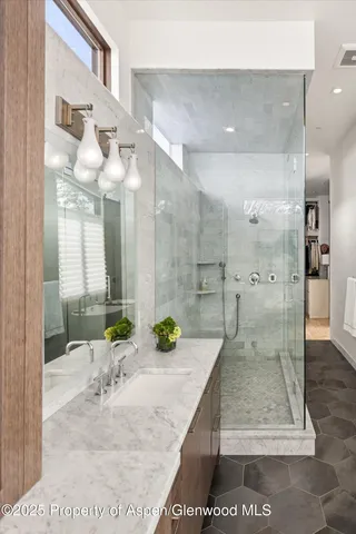 a bathroom with a granite countertop sink a mirror and shower