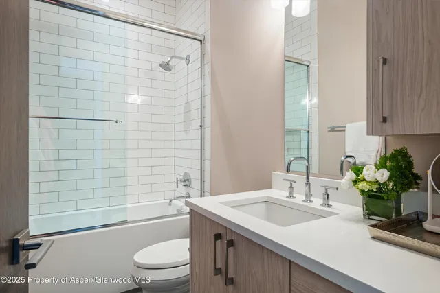 a bathroom with a granite countertop sink a toilet and shower