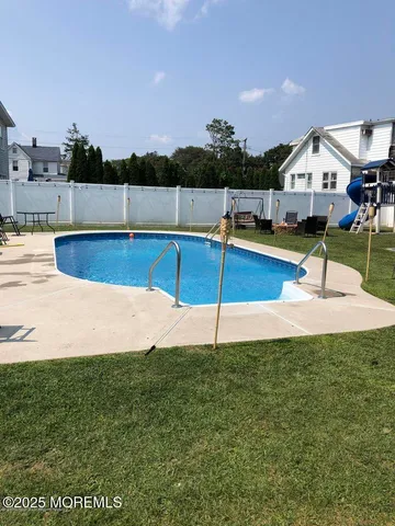 a view of swimming pool with seating area and trees in the background