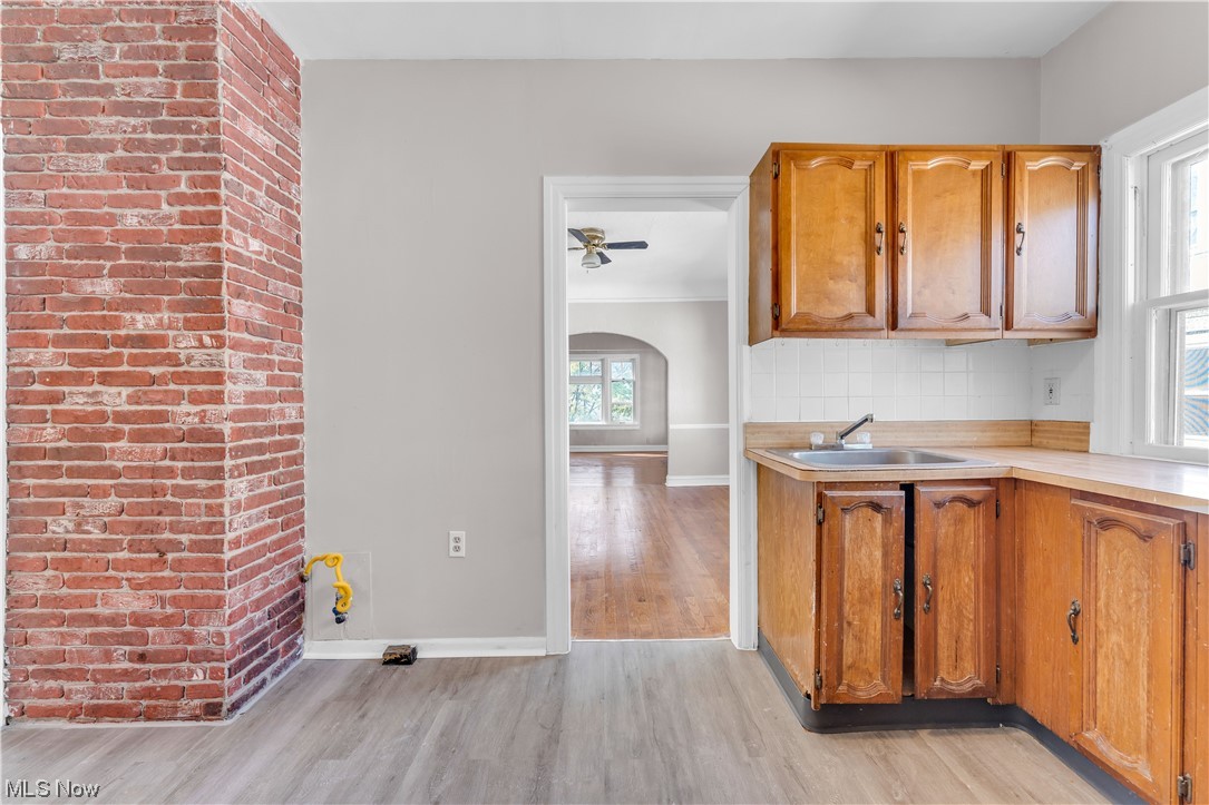 1499 Sherbrook Road South Euclid, OH 44121 - Photo 14 of 41 Kitchen with tasteful backsplash, brick wall, light hardwood floors, ceiling fan, and sink