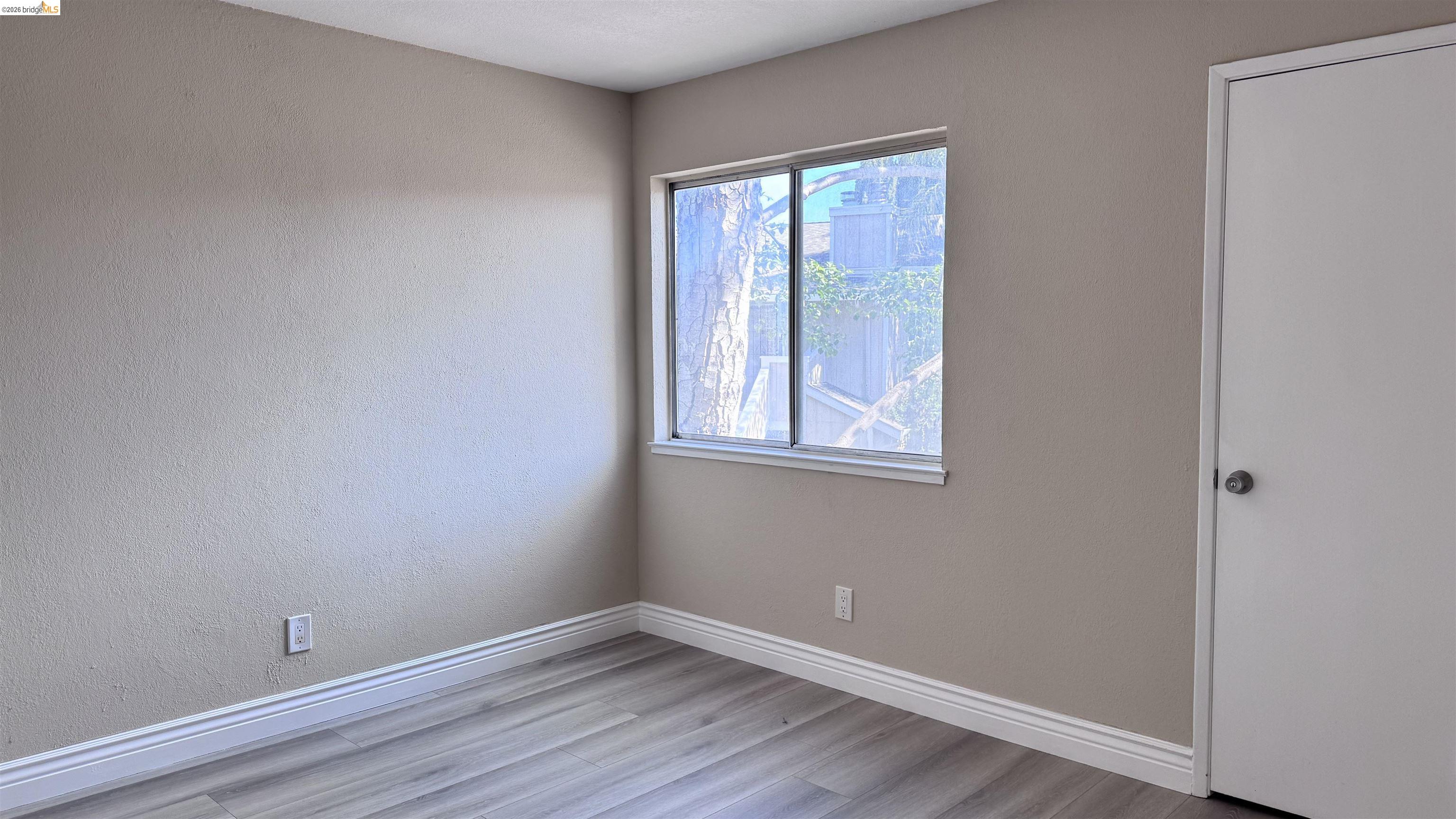 23 Raintree Court, Unit 15 Hayward, CA 94544 - Photo 5 of 15 Empty room with light wood-type flooring and a textured wall