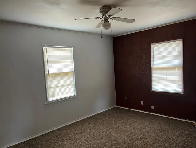 an empty room with a window and a fan