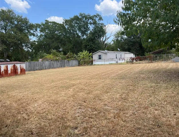 a backyard of a house with table and chairs a fire pit and a large tree