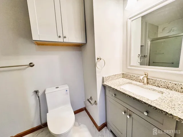 a bathroom with a granite countertop toilet sink and mirror
