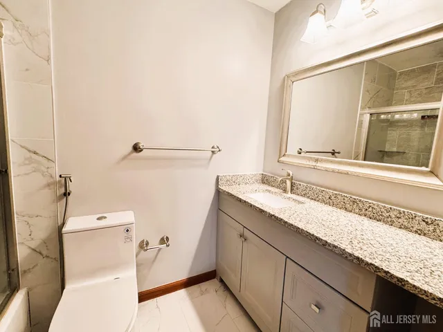 a bathroom with a granite countertop sink toilet and shower