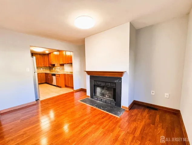 a view of empty room with a fireplace and wooden floor
