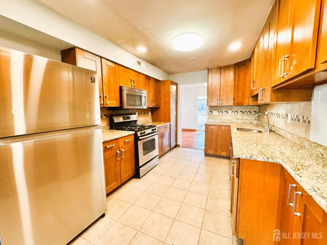 a kitchen with stainless steel appliances granite countertop a refrigerator a stove and a sink with wooden floor