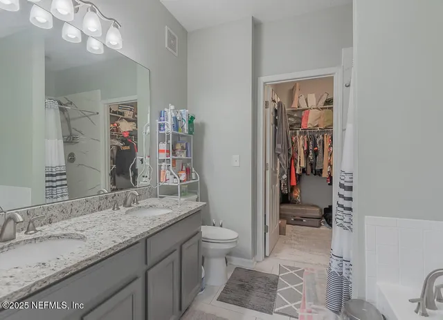 a spacious bathroom with a granite countertop sink a toilet and a shower