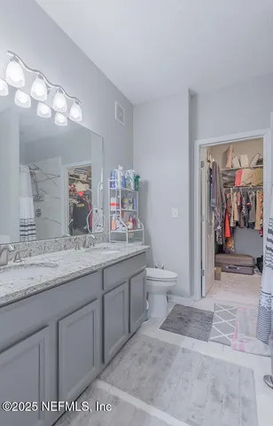 a spacious bathroom with a granite countertop sink a toilet and a mirror