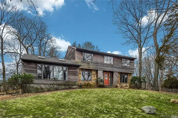 a view of a brick house with a big yard and large trees