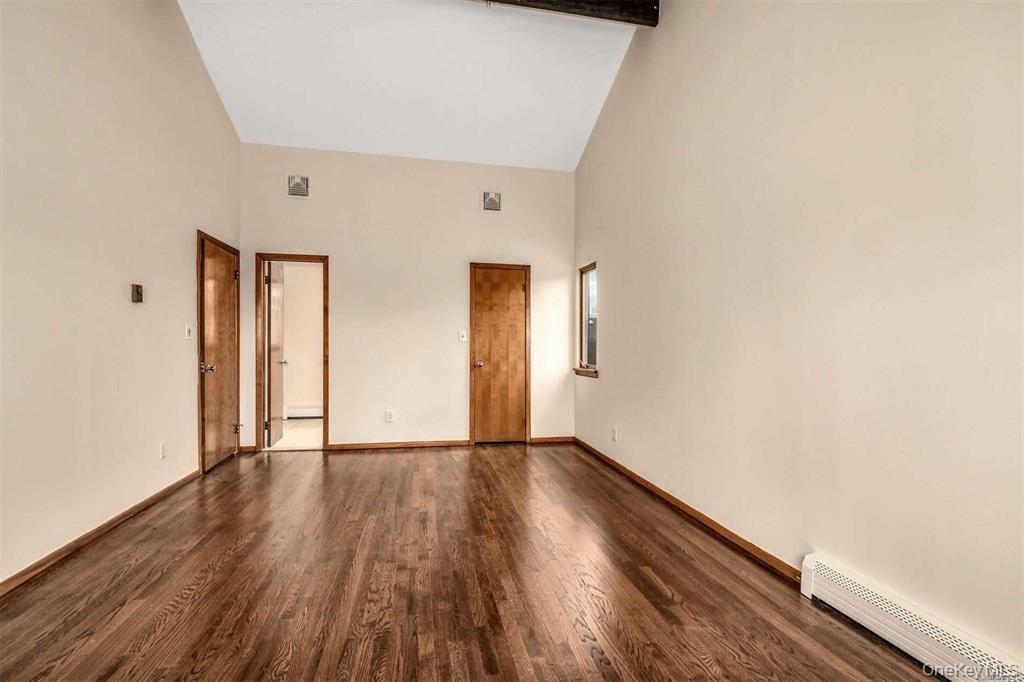36 Bevin Road Northport, NY 11768 - Photo 14 of 26 Unfurnished bedroom with high vaulted ceiling, a baseboard heating unit, dark wood finished floors, and beam ceiling