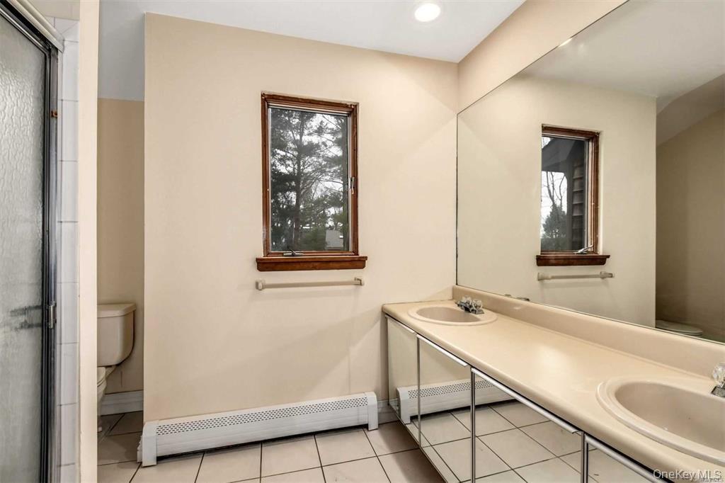 36 Bevin Road Northport, NY 11768 - Photo 15 of 26 Bathroom with baseboard heating, double vanity, an enclosed shower, and light tile patterned flooring