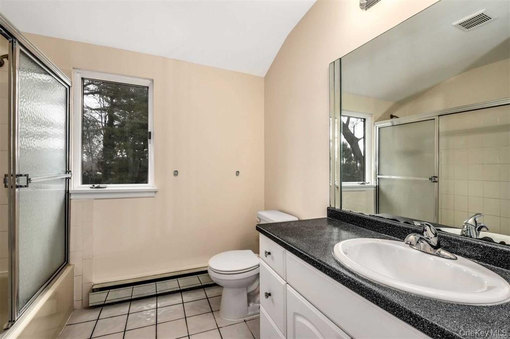 36 Bevin Road Northport, NY 11768 - Photo 16 of 26 Full bath with a baseboard radiator, vanity, vaulted ceiling, shower / bath combination with glass door, and light tile patterned floors