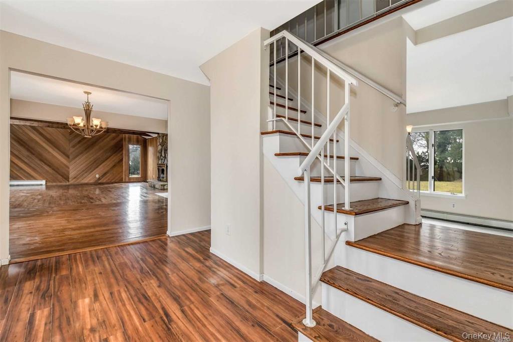 36 Bevin Road Northport, NY 11768 - Photo 4 of 26 Stairway featuring wood finished floors, a chandelier, and a baseboard radiator