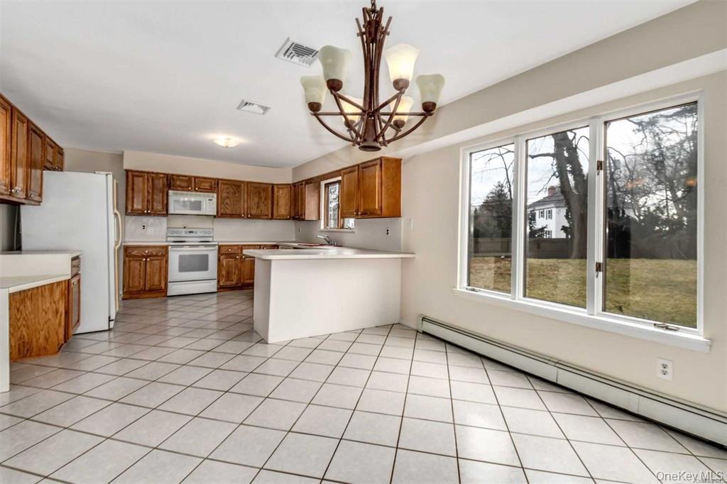 36 Bevin Road Northport, NY 11768 - Photo 7 of 26 Kitchen featuring a baseboard radiator, light countertops, white appliances, and brown cabinets
