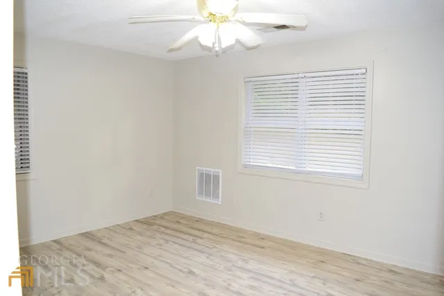 an empty room with a window and a ceiling fan