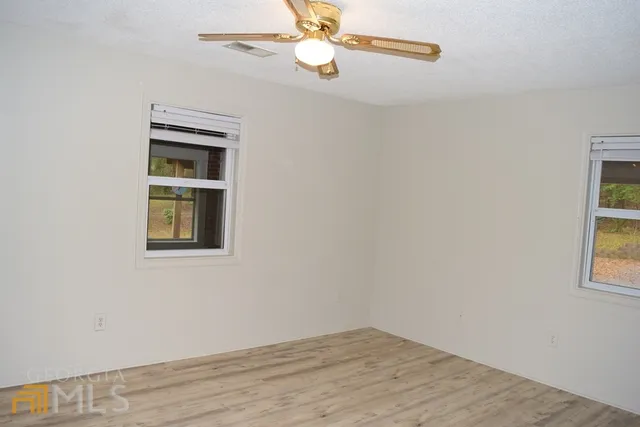 an empty room with windows and fan