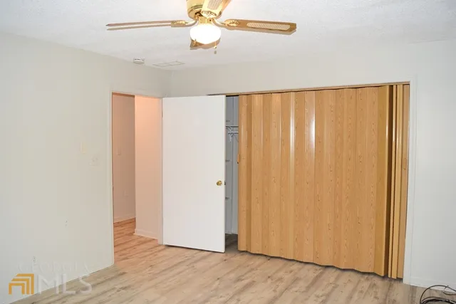 an empty room with wooden floor closet and windows