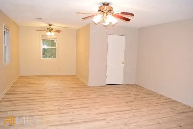 a view of an empty room with window and a kitchen