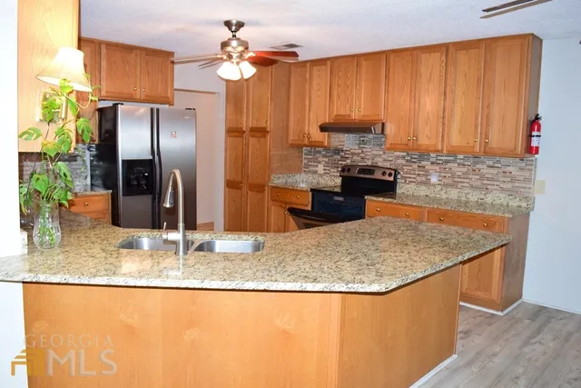 a kitchen with stainless steel appliances granite countertop a sink a refrigerator and a granite counter tops