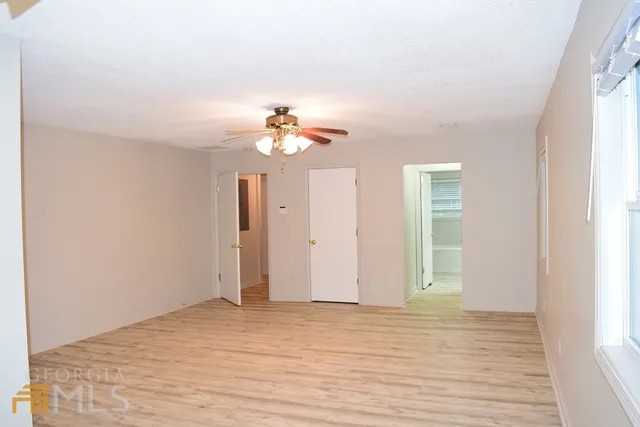 a view of empty room with wooden floor and fan