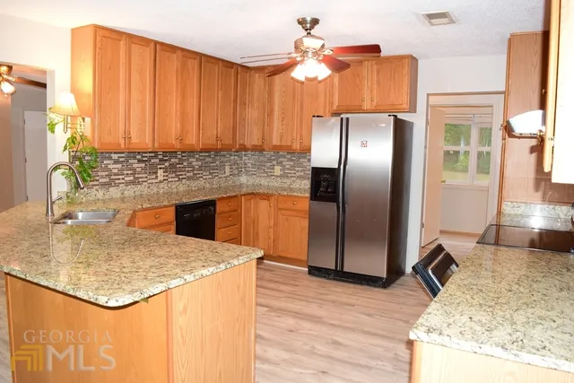 a kitchen with stainless steel appliances kitchen island granite countertop a refrigerator a stove and a sink with wooden floor