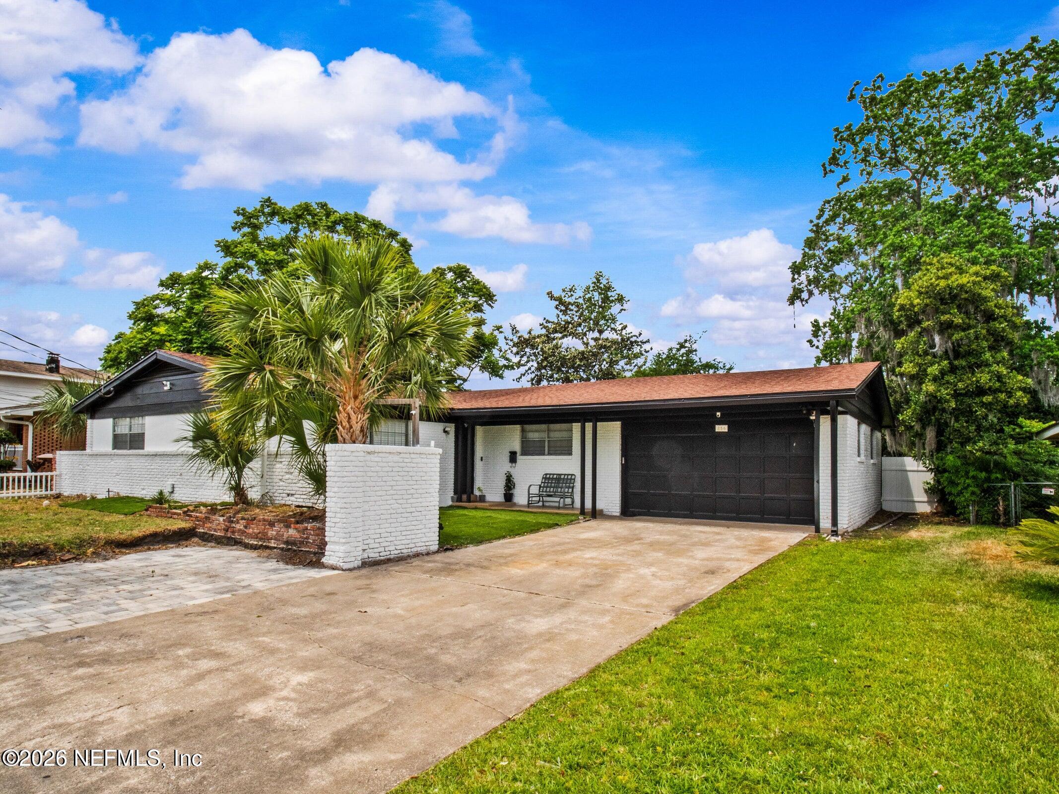 a front view of a house with a garden and trees