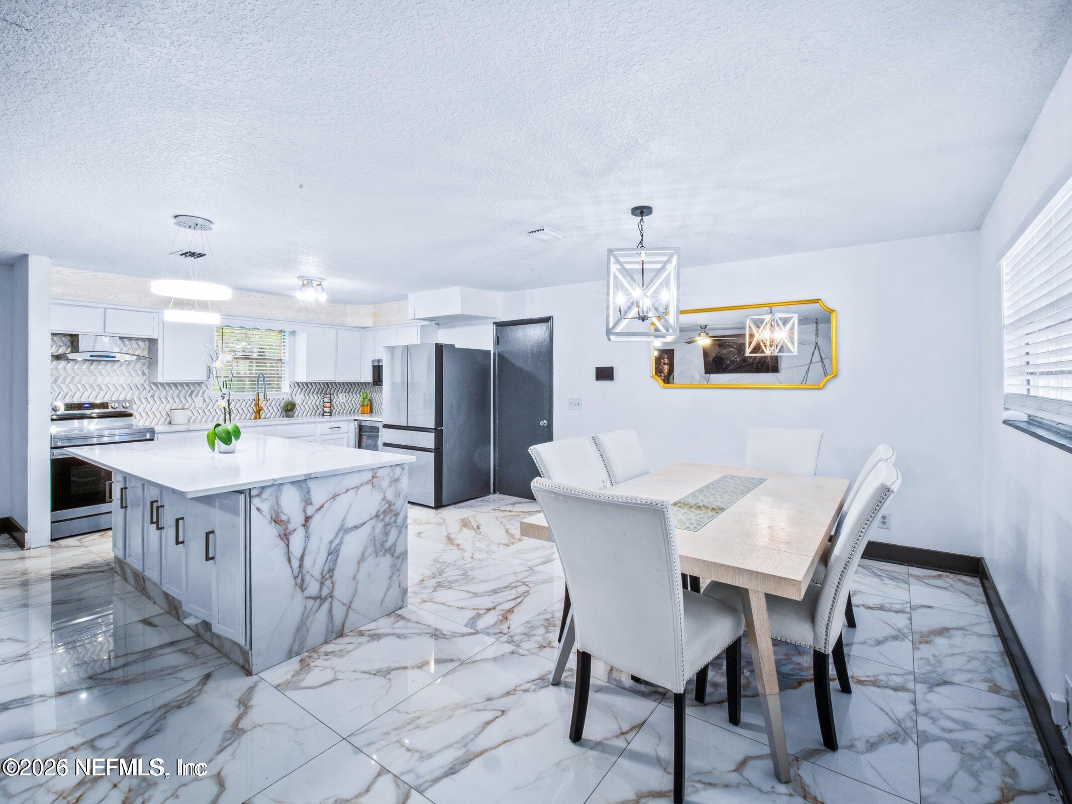 856 Palermo Road Jacksonville, FL 32216 - Photo 5 of 17 a kitchen with stainless steel appliances kitchen island granite countertop a table chairs and a refrigerator