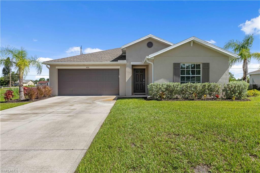 Ranch-style house featuring a garage, stucco siding, concrete driveway, a front yard, and roof with shingles
