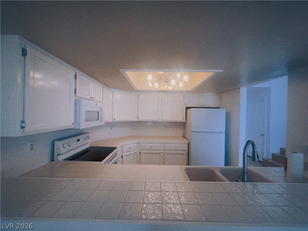 6250 West Flamingo Road, Unit 60 Las Vegas, NV 89103 - Photo 7 of 23 Functional kitchen with ample cabinetry, a tiled counter, and essential appliances awaits your culinary touch.