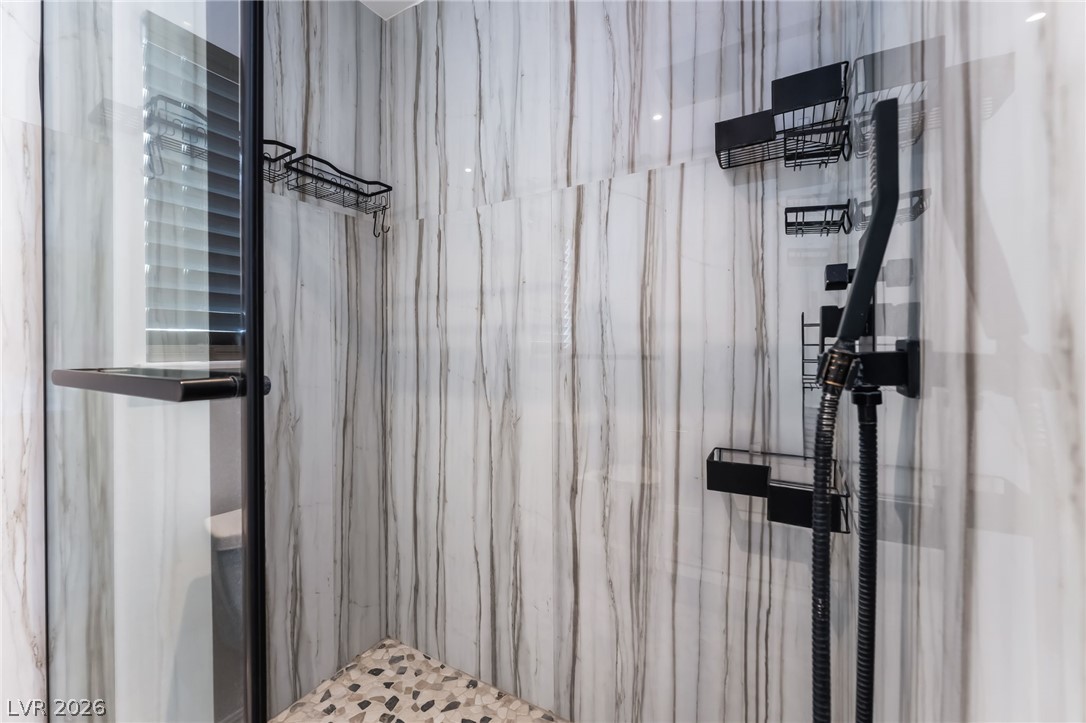9028 Cypress Point Road Las Vegas, NV 89117 - Photo 3 of 39 A modern shower with sleek black fixtures and a stylish marble-patterned wall offers a refreshing experience.