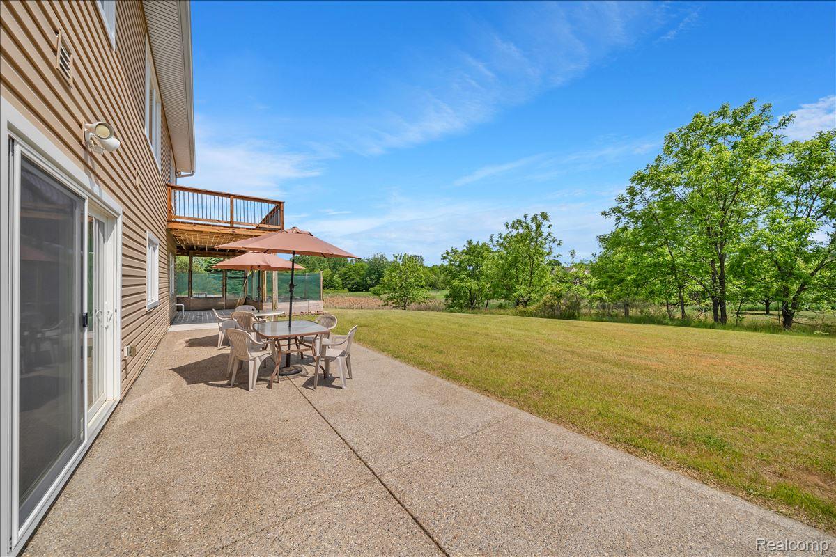 4266 McCandlish Road Grand Blanc, MI 48439 - Photo 55 of 68 Expansive concrete patio offering a broad lawn area, mature trees, and a multi-level deck with wooden railing