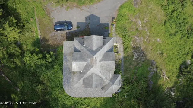 an aerial view of residential house with outdoor space and trees all around
