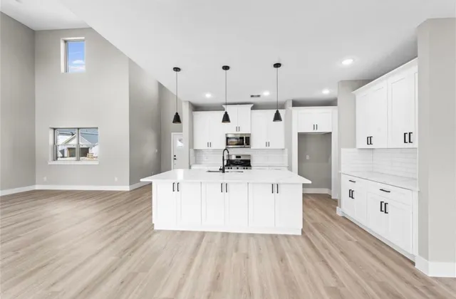 a large white kitchen with a large window a sink and stainless steel appliances