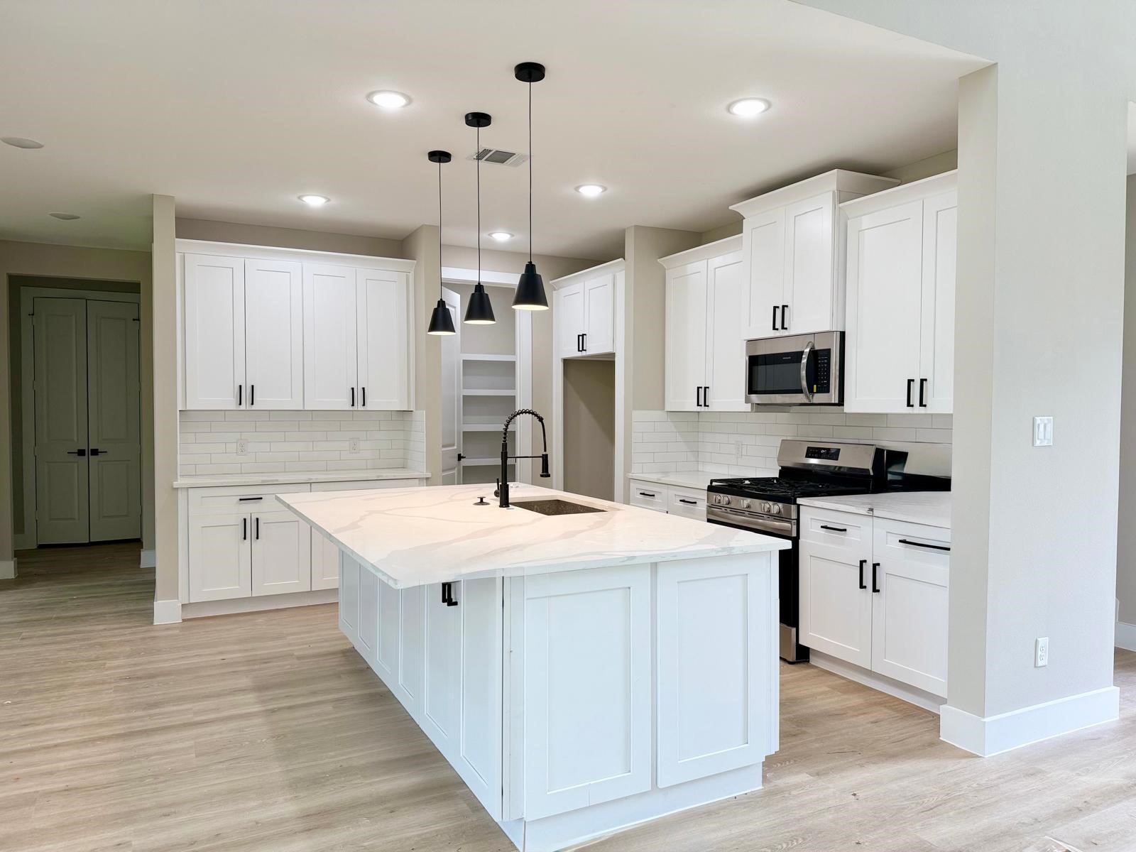 2518 Liguria Ln Spring Spring, TX 77388 - Photo 6 of 36 a kitchen with stainless steel appliances kitchen island granite countertop a sink stove oven and white cabinets with wooden floor