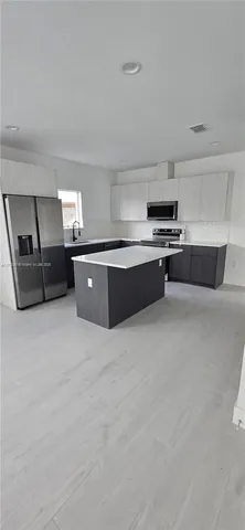 a large kitchen with stainless steel appliances a stove a sink dishwasher and white cabinets