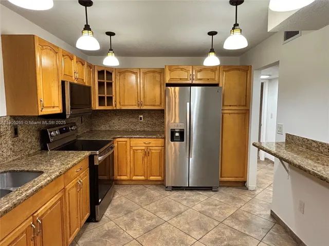 a kitchen with stainless steel appliances granite countertop a stove a microwave and a sink