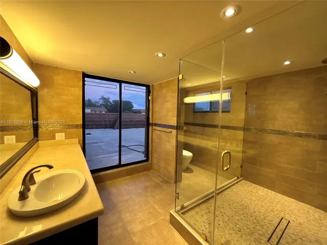 a bathroom with a granite countertop sink a mirror and shower