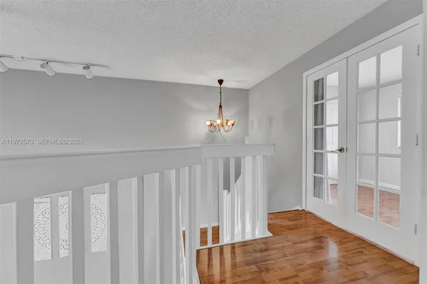 a view of a livingroom with wooden floor staircase and a kitchen space