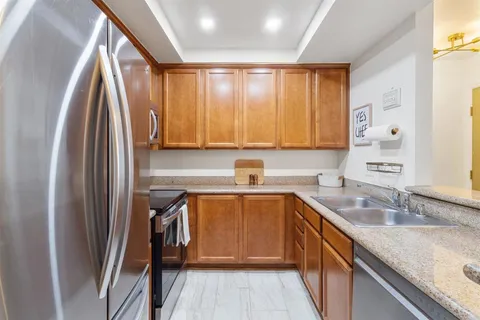 a kitchen with stainless steel appliances granite countertop a sink refrigerator and cabinets