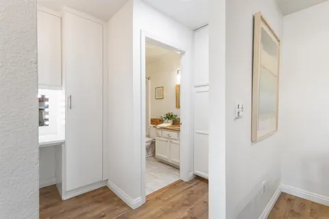 a view of a hallway with wooden floor and a bathroom