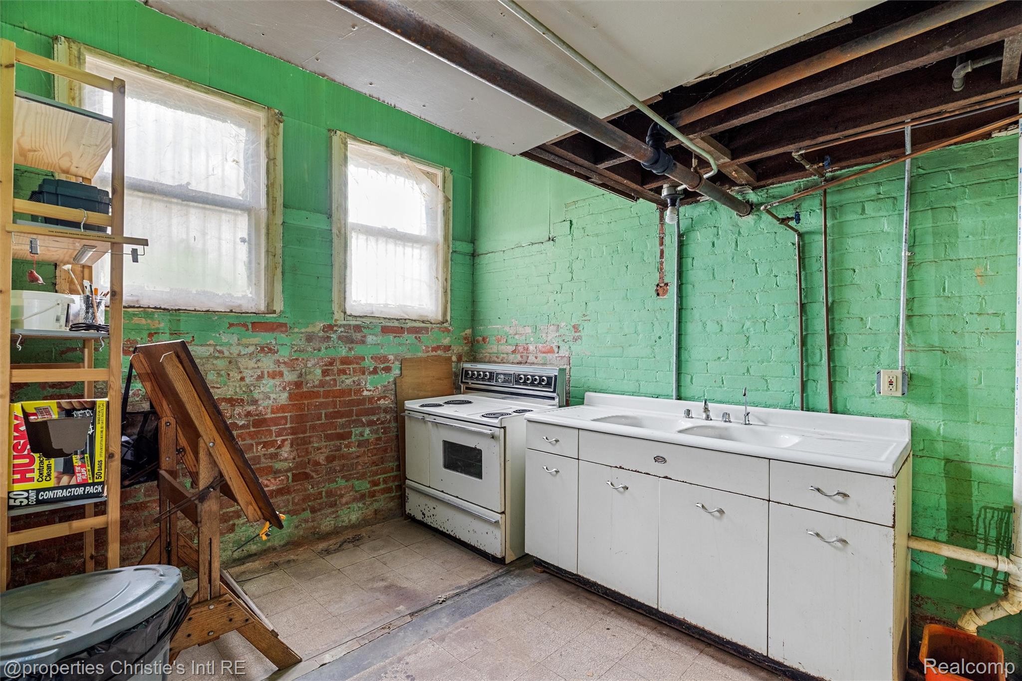36 Longfellow Street Detroit, MI 48202 - Photo 66 of 81 Kitchen with light flooring, white range with electric cooktop, light countertops, white cabinets, and brick wall