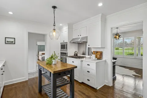 a kitchen with stainless steel appliances granite countertop a stove and white cabinets with wooden floor
