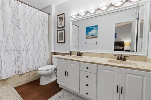 a bathroom with a toilet sink double vanity and mirror