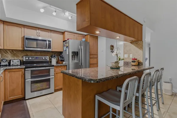 a kitchen with stainless steel appliances kitchen island granite countertop a stove a sink and a microwave