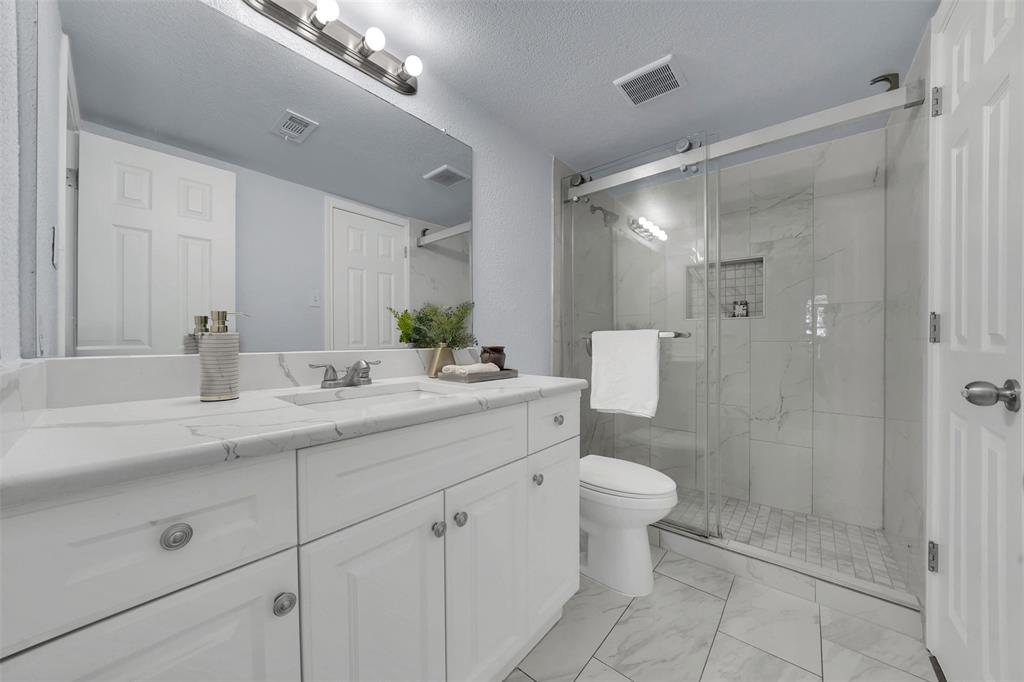 1024 East Peters Colony Road Carrollton, TX 75007 - Photo 22 of 38 Full bathroom featuring vanity, a marble finish shower, a textured ceiling, and light marble finish flooring