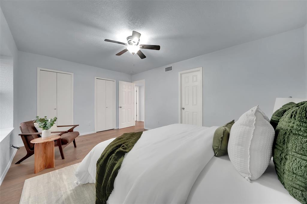 1024 East Peters Colony Road Carrollton, TX 75007 - Photo 25 of 38 Bedroom featuring two closets, light wood-type flooring, ceiling fan, and a textured ceiling
