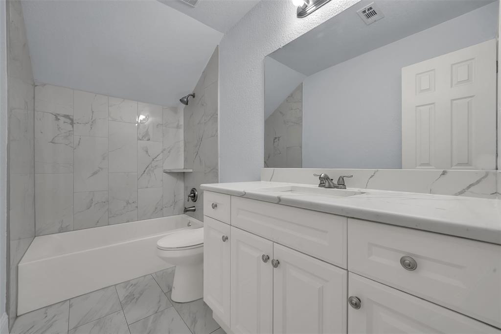 1024 East Peters Colony Road Carrollton, TX 75007 - Photo 31 of 38 Full bathroom with vanity, shower / washtub combination, light marble finish floors, vaulted ceiling, and a textured wall