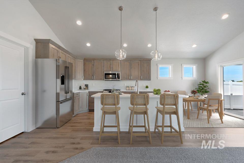 1668 Kayak Road Emmett, ID 83617 - Photo 7 of 32 Kitchen with stainless steel appliances, lofted ceiling, light countertops, backsplash, and light wood-style floors