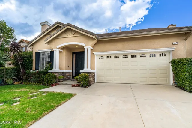 a view of a house with brick walls and a yard with plants